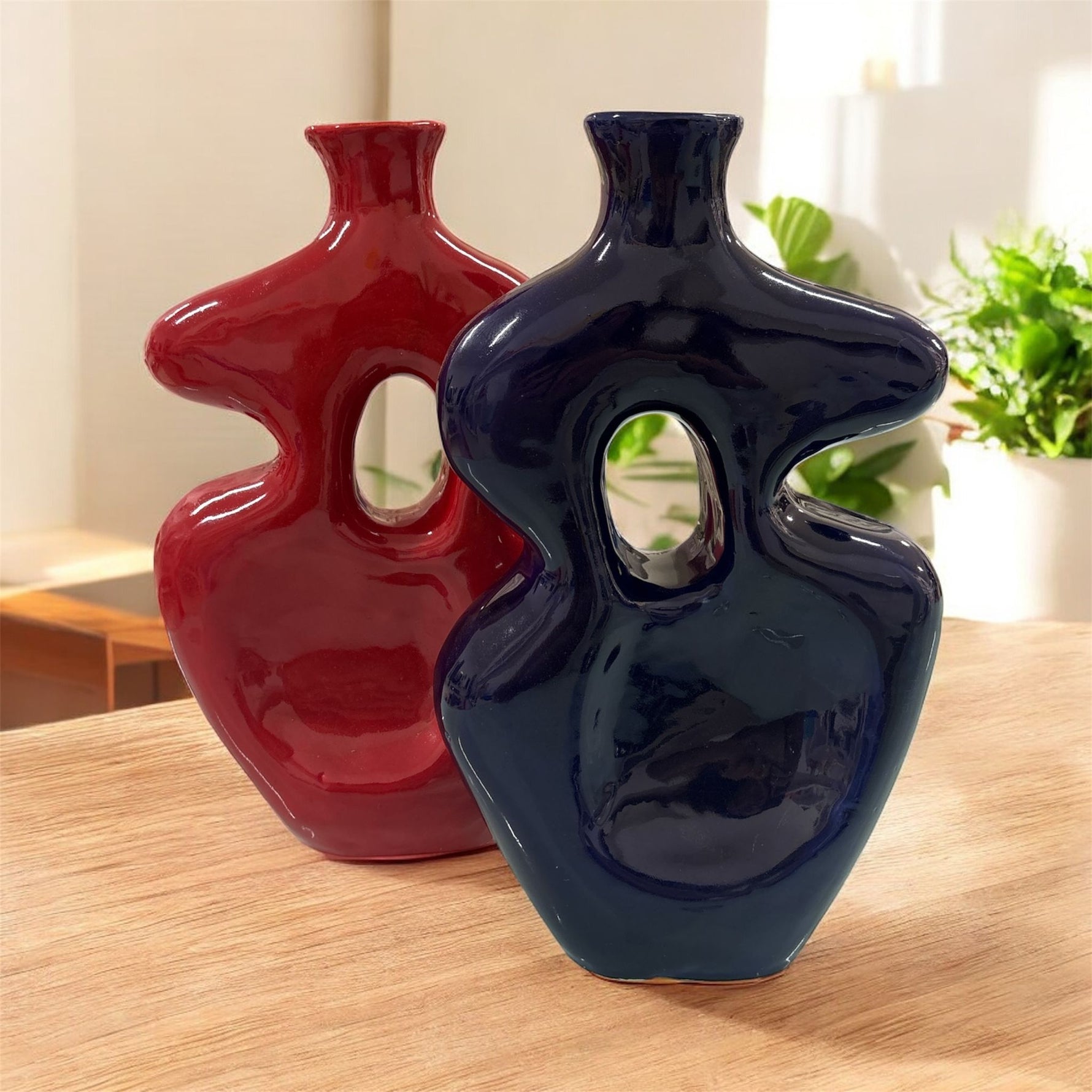 Vasi scultorei in ceramica rosso e blu esposti insieme su tavolo in ambiente moderno