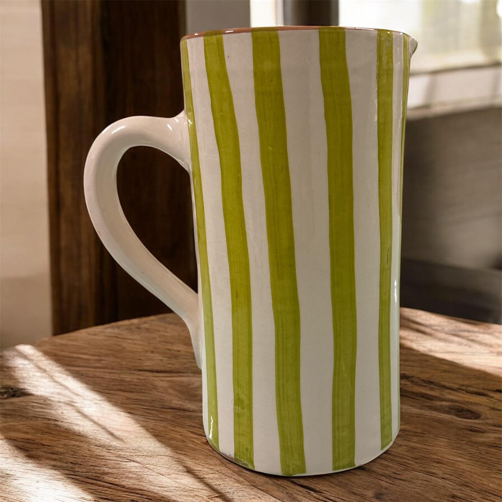 Vaso artigianale in ceramica a righe verde e terracotta con un manico, fatto a mano, stile naturale, ambientato in interno luminoso