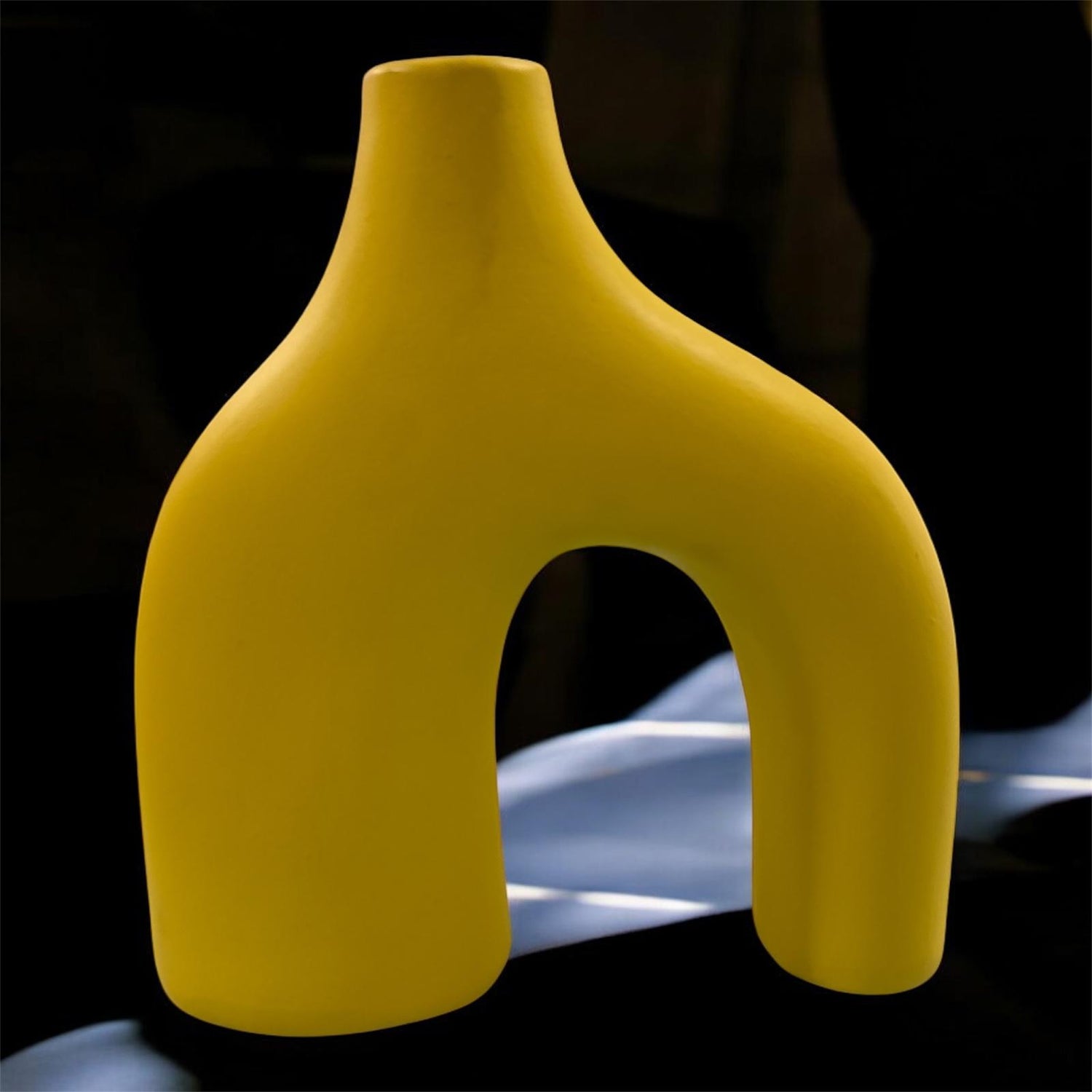 Vaso artigianale giallo in ceramica con doppio piede, design moderno e scultoreo.
