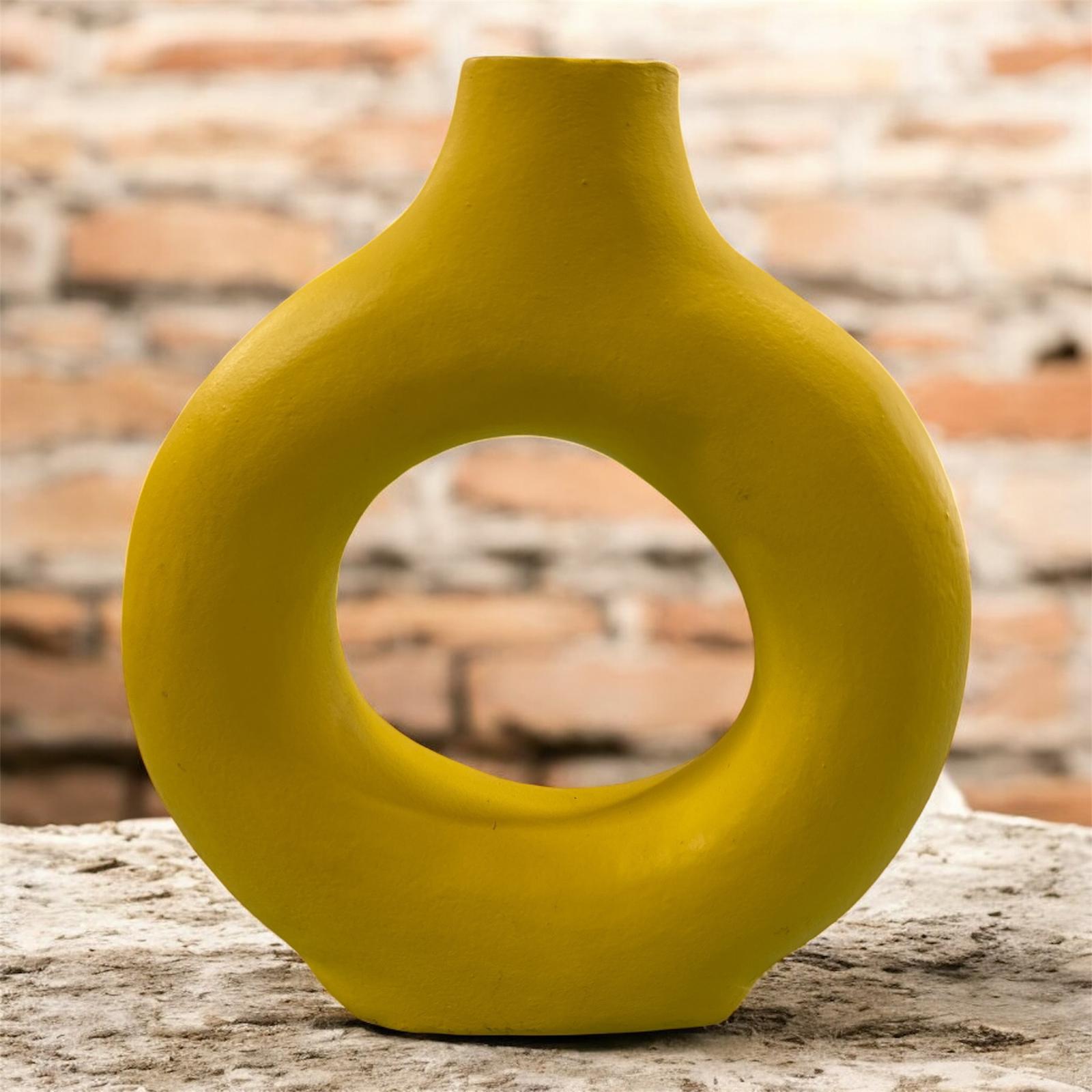 Vaso giallo opaco in ceramica con foro centrale, ambientato su superficie chiara.
