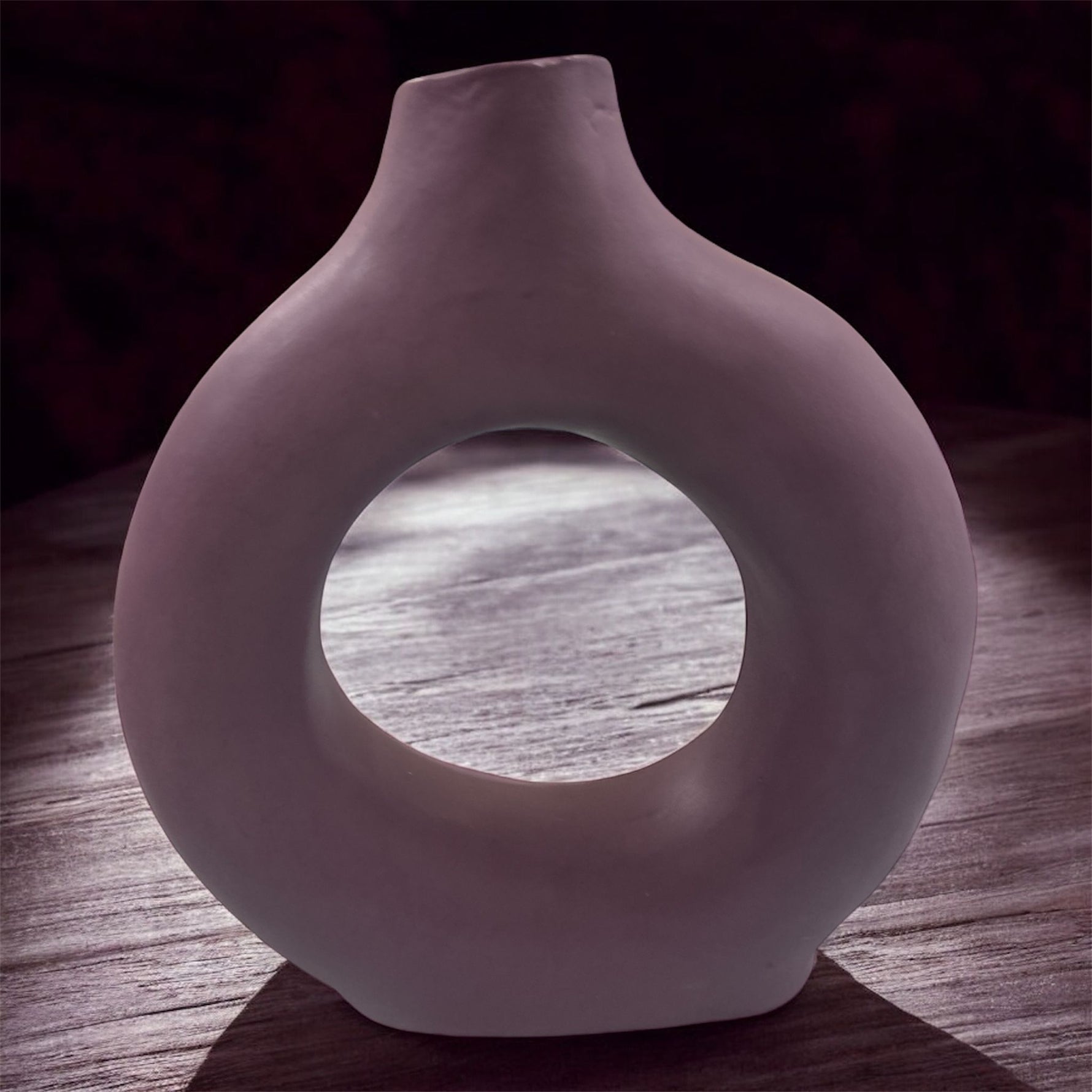 Vaso artigianale lavanda in ceramica con design a foro centrale, ambientato su tavolo scuro.