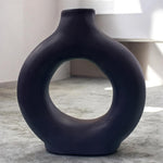 Vaso artigianale blu notte in ceramica con foro centrale, ambientato in un interno moderno.