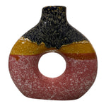 Vaso in ceramica fatto a mano Marika De Paola con foro centrale e sfumature rosa, giallo e blu visto frontalmente.