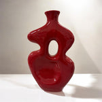Vaso in ceramica rosso scultoreo su superficie luminosa in ambiente moderno