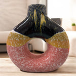 Vaso in ceramica tricolore con apertura centrale, fotografato in ambiente moderno