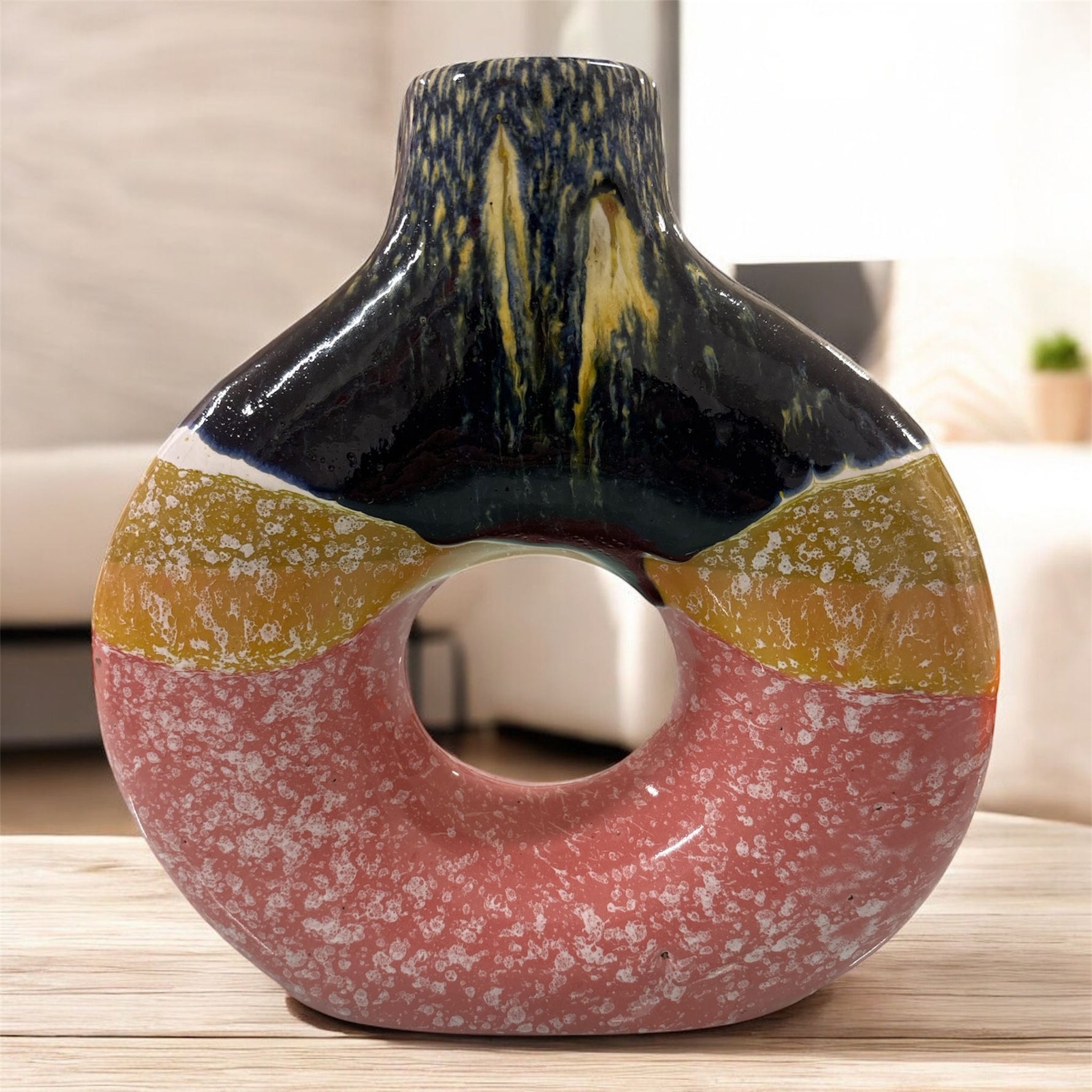 Vaso in ceramica tricolore con apertura centrale, fotografato in ambiente moderno