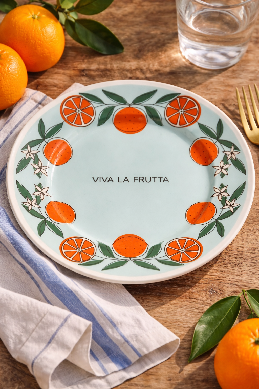 piatto Viva la Frutta arance diametro 21 cm ambientato su tavolo in legno con arance e tovaglietta mediterranea
