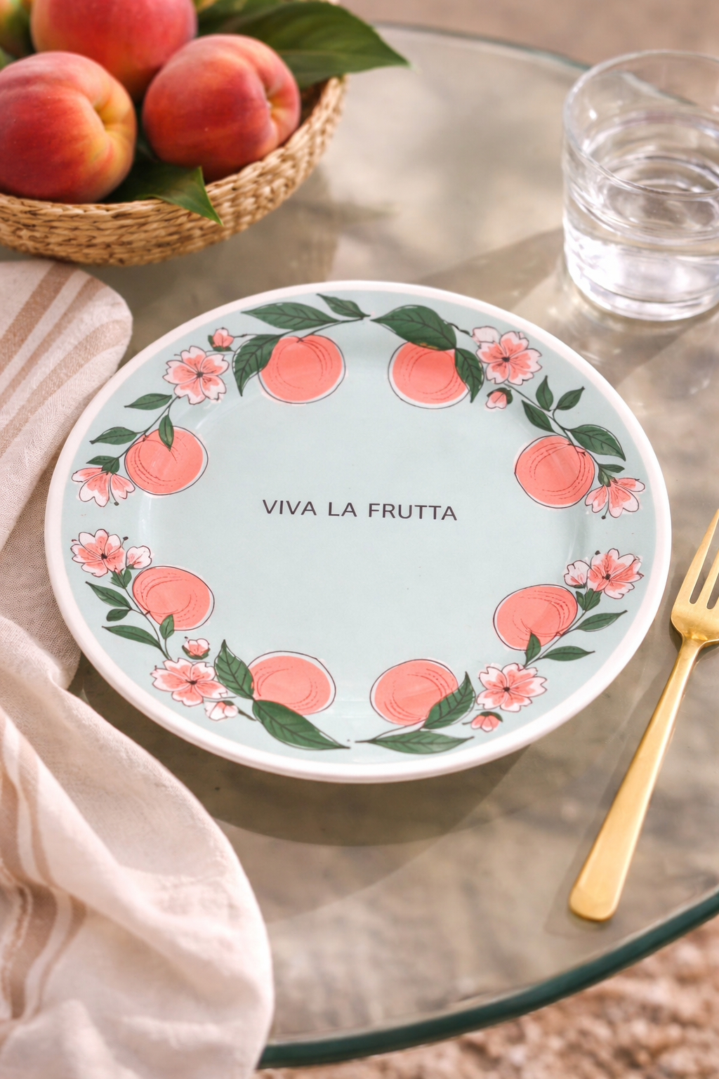 piatto Viva la Frutta pesche diametro 21 cm ambientato su tavolo in vetro con pesche fresche e tovaglietta beige
