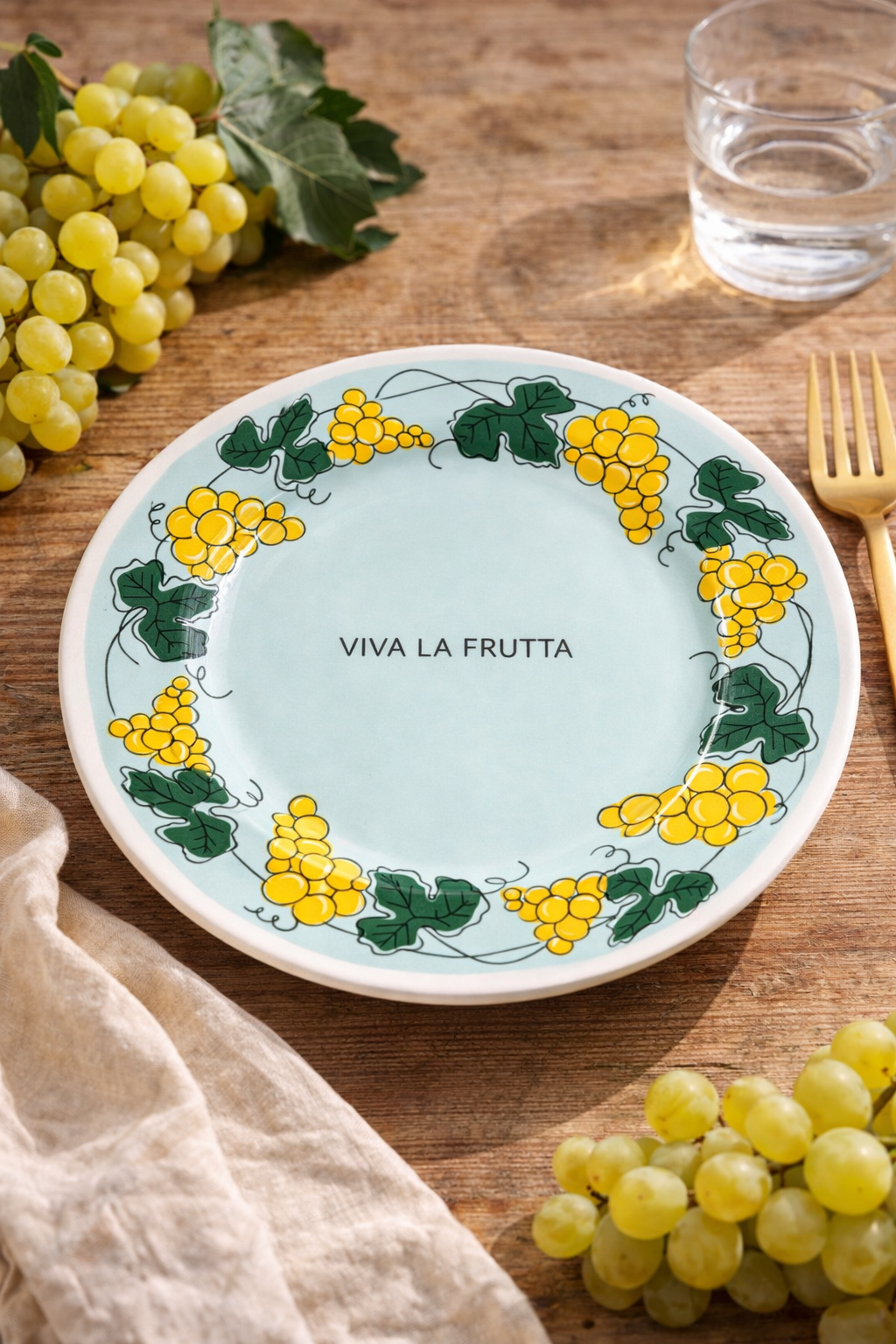 piatto Viva la Frutta uva diametro 21 cm ambientato su tavolo in legno con grappoli d’uva e tovaglietta in lino
